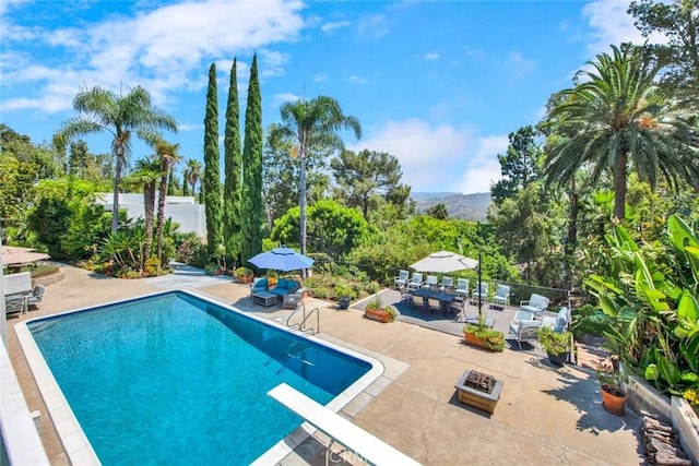 view of pool featuring a diving board and a patio