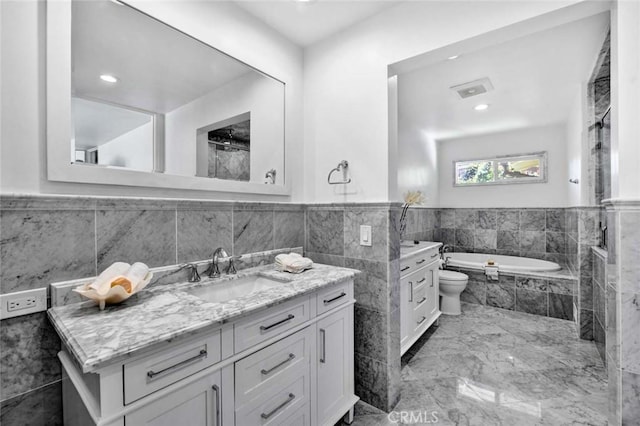 bathroom featuring tiled bath, toilet, and vanity