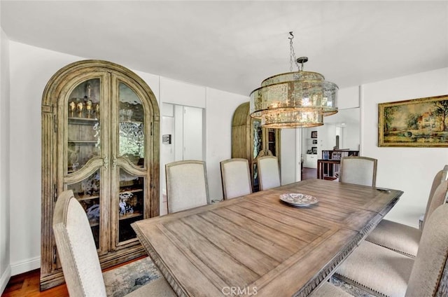 dining space with hardwood / wood-style floors and a notable chandelier