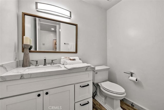 bathroom featuring wood-type flooring, toilet, and vanity