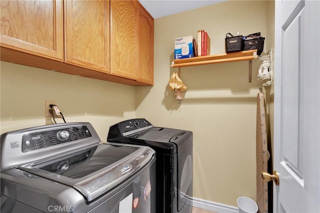 clothes washing area with cabinets and separate washer and dryer