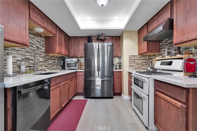 kitchen featuring dishwasher, wall chimney range hood, double oven range, stainless steel refrigerator, and a tray ceiling