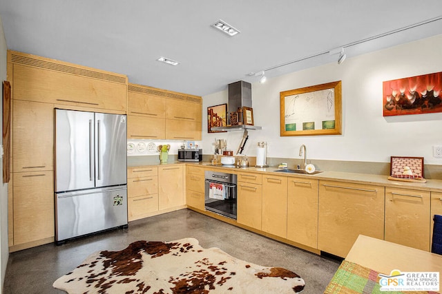 kitchen featuring appliances with stainless steel finishes, sink, light brown cabinets, and wall chimney range hood