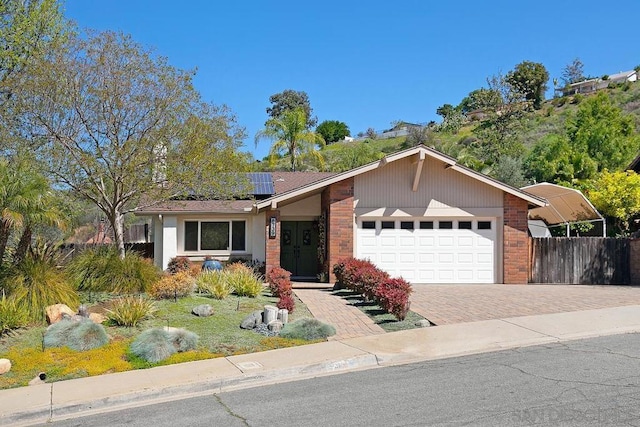 ranch-style house featuring a garage and solar panels