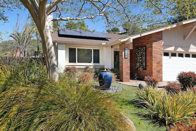 ranch-style house featuring a garage and solar panels