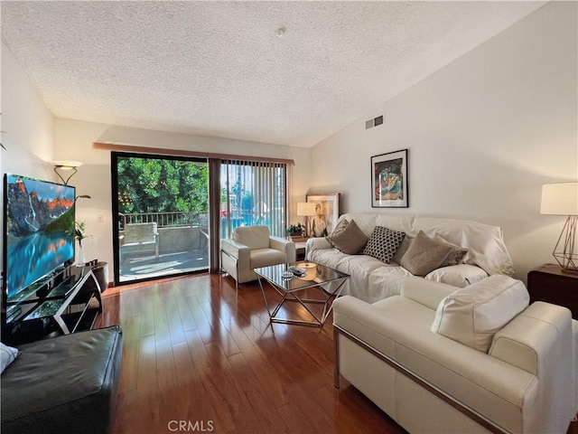 living room with lofted ceiling, dark wood-type flooring, and a textured ceiling