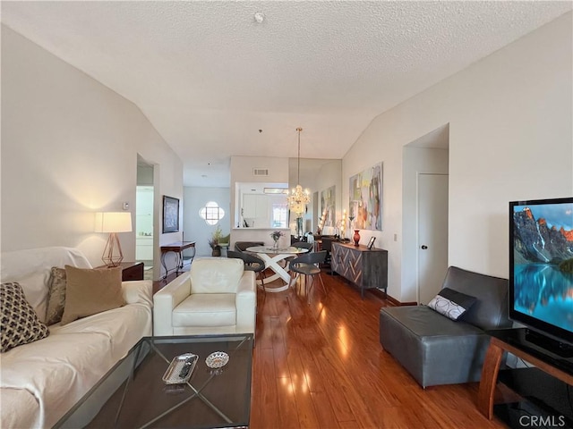 living room with lofted ceiling, hardwood / wood-style flooring, a textured ceiling, and an inviting chandelier