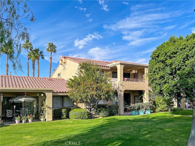 back of house featuring a balcony and a yard