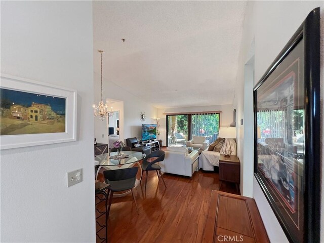 living room featuring lofted ceiling, dark hardwood / wood-style flooring, and a chandelier