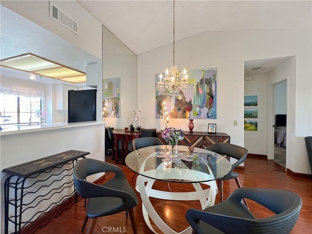 dining area featuring an inviting chandelier, hardwood / wood-style flooring, and vaulted ceiling