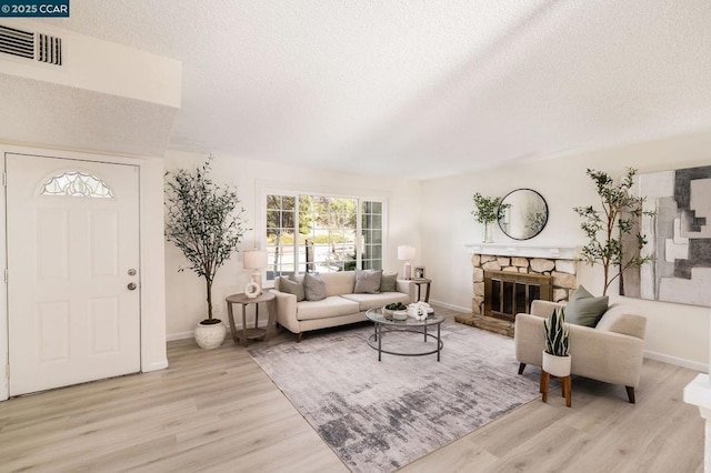 living room featuring a textured ceiling, a fireplace, and light hardwood / wood-style flooring