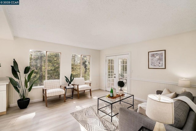 living room featuring french doors, light hardwood / wood-style floors, and a textured ceiling