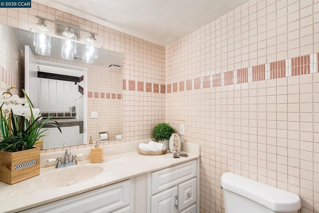 bathroom featuring vanity, tile walls, and toilet