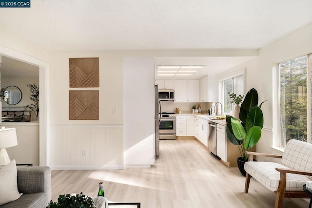 kitchen featuring white cabinets, appliances with stainless steel finishes, light hardwood / wood-style flooring, and sink