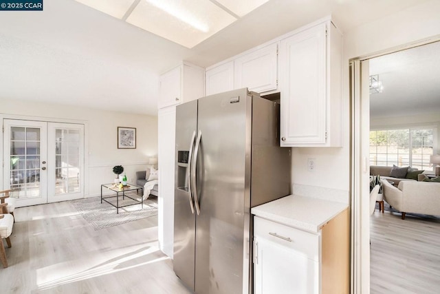 kitchen with white cabinets, stainless steel fridge, light hardwood / wood-style floors, and french doors