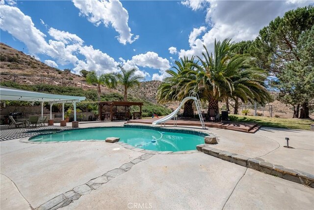 view of pool with a water slide and a patio