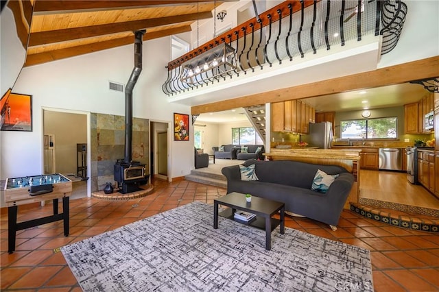 tiled living room with wooden ceiling, beam ceiling, a wood stove, and high vaulted ceiling