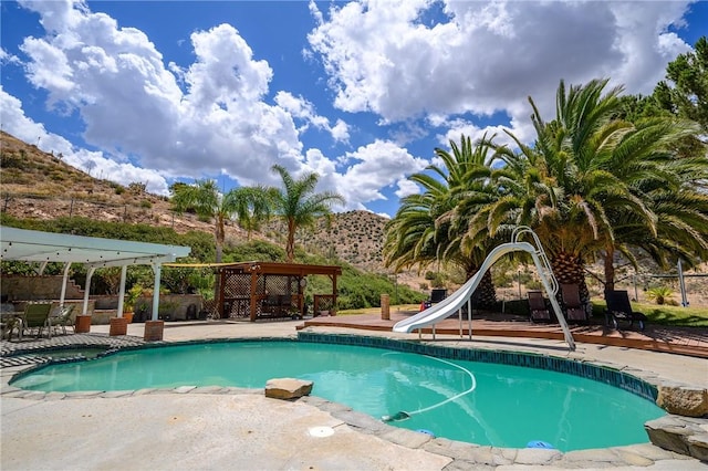 view of swimming pool with a mountain view, a water slide, and a pergola