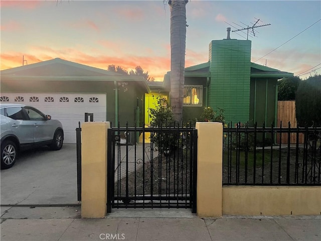 view of front facade with a fenced front yard, driveway, a chimney, and an attached garage