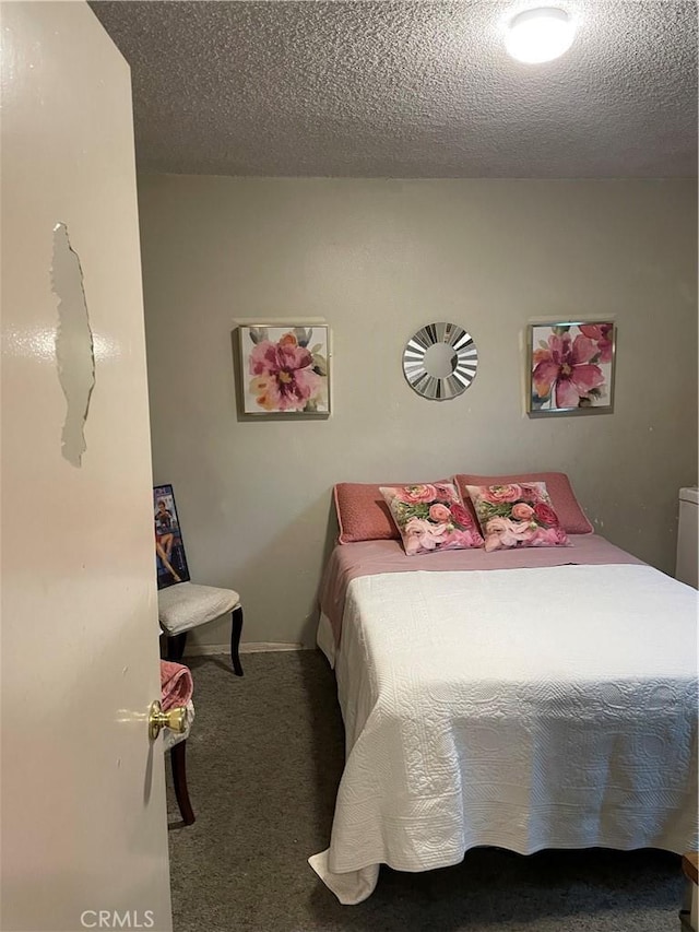 carpeted bedroom featuring a textured ceiling and baseboards