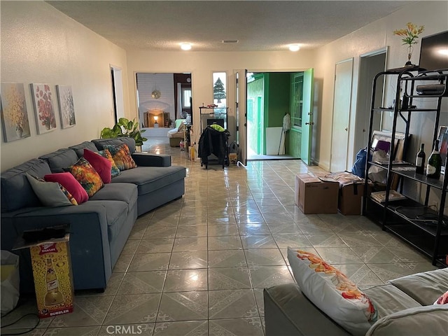 living area with tile patterned flooring, visible vents, and a textured ceiling