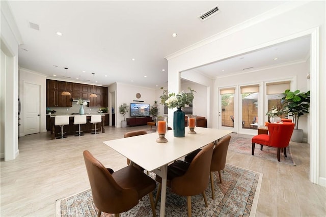 dining space featuring crown molding and light hardwood / wood-style flooring