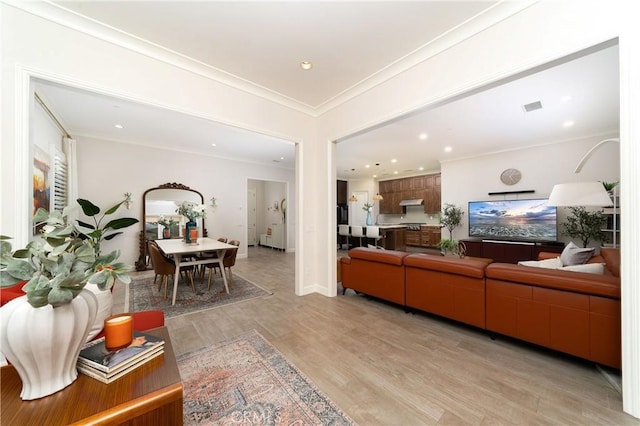 living room with ornamental molding and light hardwood / wood-style flooring