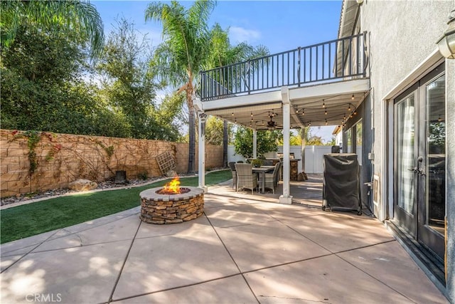 view of patio / terrace with ceiling fan, a grill, a balcony, and a fire pit