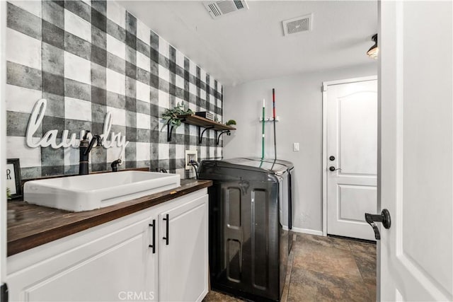 clothes washing area featuring washing machine and dryer, sink, and cabinets