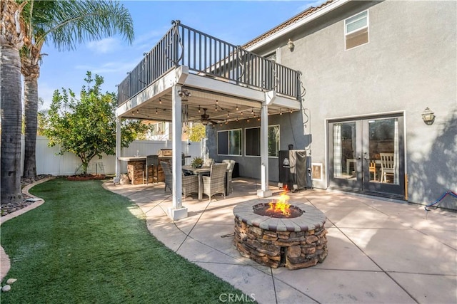 view of patio featuring a balcony, an outdoor fire pit, a bar, and french doors