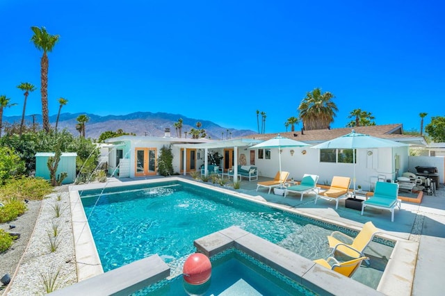 view of swimming pool with a mountain view, french doors, and a patio