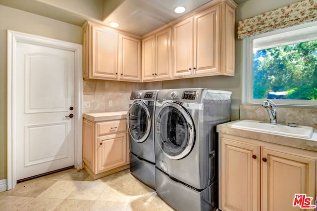 clothes washing area featuring cabinets, sink, and independent washer and dryer