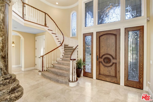 entrance foyer with a towering ceiling and ornamental molding