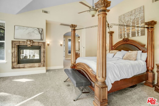 carpeted bedroom with ceiling fan, a multi sided fireplace, and lofted ceiling