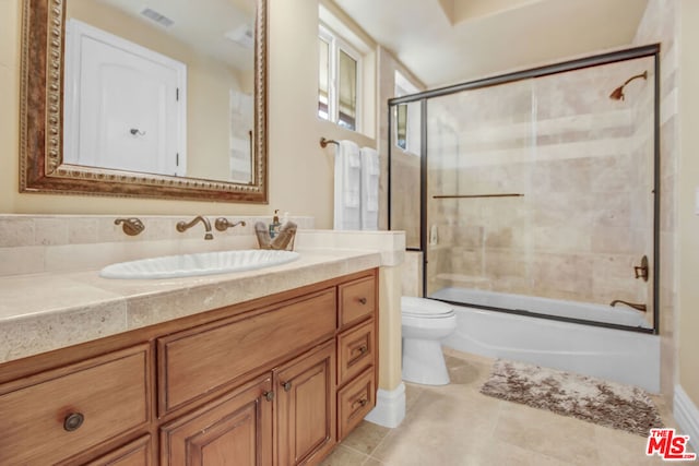 full bathroom featuring combined bath / shower with glass door, vanity, and toilet