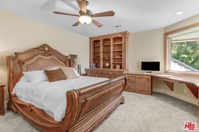 carpeted bedroom with ceiling fan and built in desk