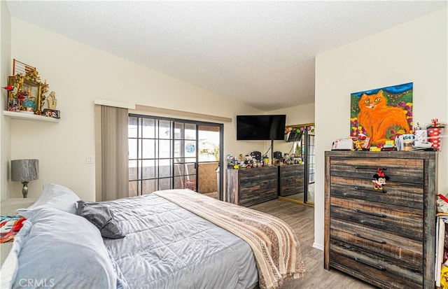 bedroom featuring vaulted ceiling, access to outside, and a textured ceiling