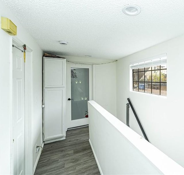 corridor with dark hardwood / wood-style floors and a textured ceiling