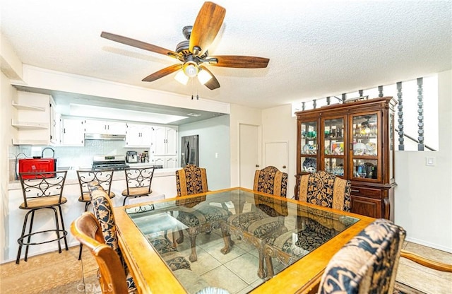 dining space featuring ceiling fan, sink, and a textured ceiling