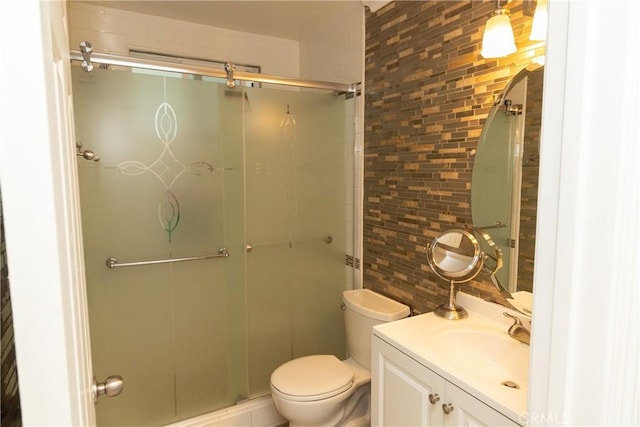 bathroom featuring toilet, tasteful backsplash, a shower with door, and vanity