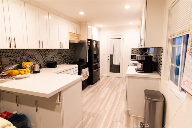 kitchen featuring white cabinets, black appliances, a kitchen breakfast bar, backsplash, and kitchen peninsula