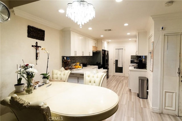 kitchen featuring decorative light fixtures, a notable chandelier, decorative backsplash, ornamental molding, and white cabinets