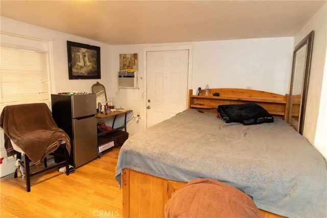 bedroom featuring light wood-type flooring, cooling unit, and stainless steel fridge