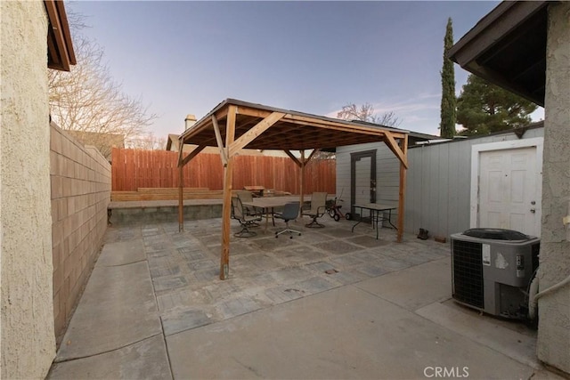 patio terrace at dusk featuring a storage shed and central air condition unit