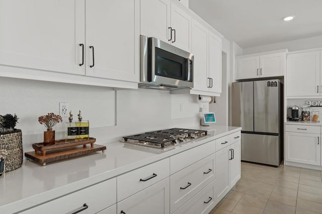 kitchen with light tile patterned floors, appliances with stainless steel finishes, and white cabinetry