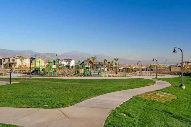 view of community featuring a playground, a mountain view, and a lawn