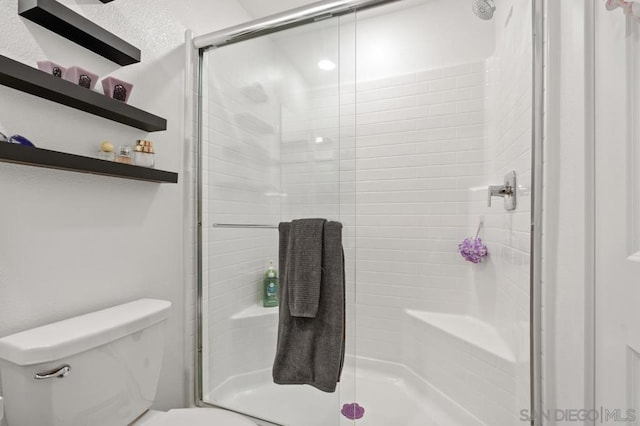 bathroom featuring toilet and a shower with shower door