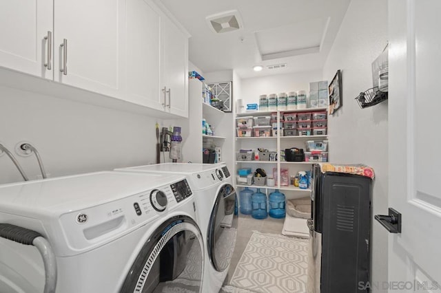 laundry room featuring cabinets, light tile patterned flooring, and washer and clothes dryer