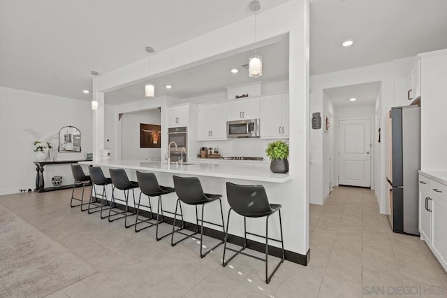 kitchen featuring white cabinetry, pendant lighting, appliances with stainless steel finishes, and a kitchen bar