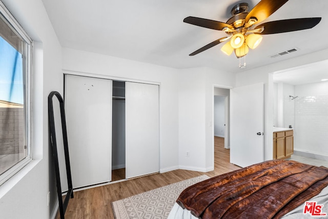 bedroom featuring ceiling fan, ensuite bathroom, a closet, and light hardwood / wood-style flooring